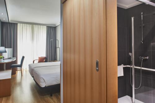 a bedroom with a bed and a bathroom with a shower at Silken Juan de Austria in Valladolid