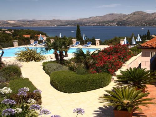a resort with a swimming pool with chairs and flowers at Villa Alegria Cavtat in Cavtat
