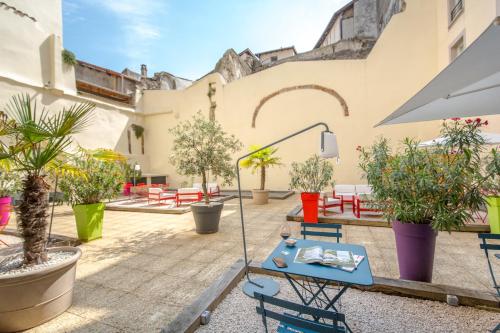 a patio with a table and chairs and potted plants at ibis Lyon Sud Vienne Saint-Louis in Vienne