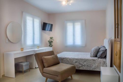a bedroom with a bed and a chair and a mirror at Blanca Serenidad Luxury Apartment in Methana