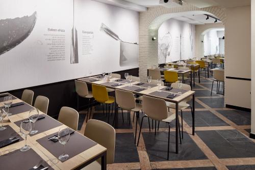 a dining room with tables and yellow chairs at Pensión Txiki Polit in Zarautz