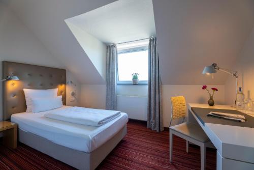a hotel room with a bed and a desk at Hotel An der Gruga in Essen