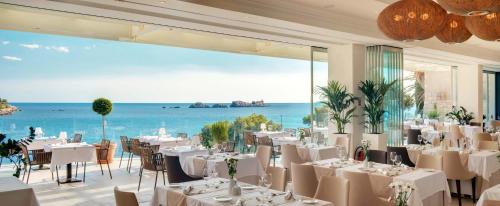
a restaurant with tables and chairs in front of a large body of water at Hotel More in Dubrovnik
