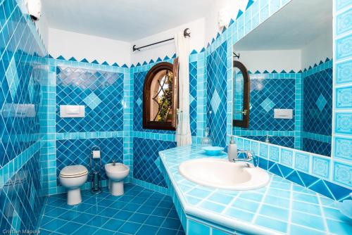 a blue tiled bathroom with a sink and a toilet at villa smeralda in Cannigione
