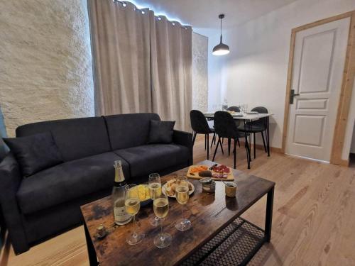 a living room with a couch and a table with wine glasses at Les appartements du centre, refaits à neuf, climatisés, hyper centre, 50m à pieds des commerces, restaurants, parking gratuit in Salies-de-Béarn