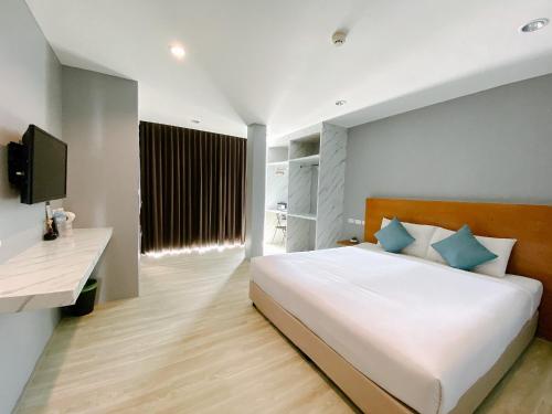1 dormitorio con 1 cama blanca grande con almohadas azules en Behind The Scene Hotel Club @ Samui, en Chaweng