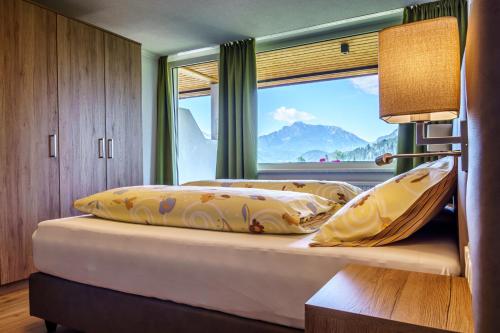 Schlafzimmer mit einem Bett und einem großen Fenster in der Unterkunft Haus Löger Apartments Pyhrn Priel in Windischgarsten