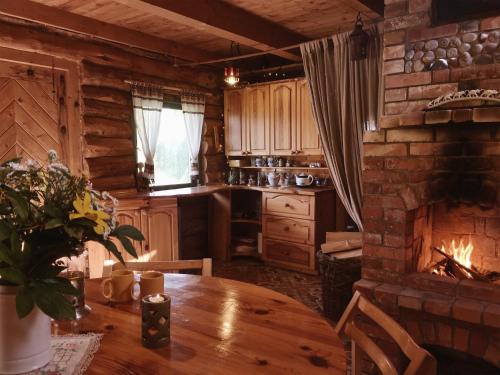 a kitchen with a wooden table and a fireplace at Namelis Atokvėpis in Čiuiniukai