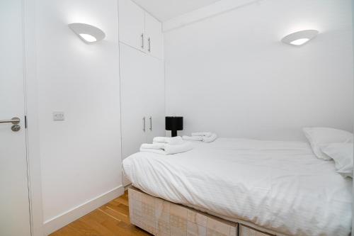 a white bedroom with a bed and white cabinets at Modern 1 Bed Flat in Holborn, London for up to 2 people with free wifi in London