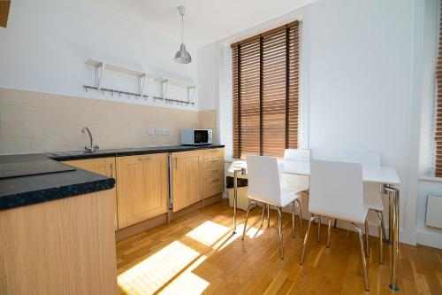 a kitchen with a table and white chairs in it at Modern 1 Bed Flat in Holborn, London for up to 2 people with free wifi in London