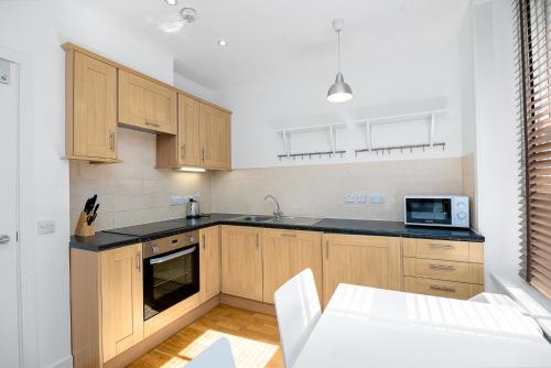 a kitchen with wooden cabinets and a microwave at Modern 1 Bed Flat in Holborn, London for up to 2 people with free wifi in London