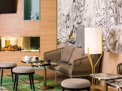 a living room with a couch and a table and chairs at Mercure Orléans Portes de Sologne in Ardon