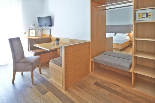 Zimmer mit einem Schreibtisch, einem Stuhl und einem Bett in der Unterkunft Hotel Post Gries in Bozen