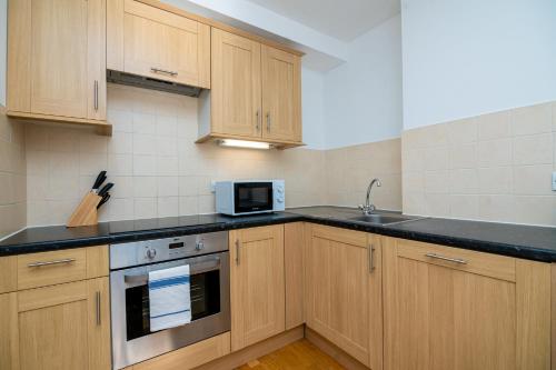 a kitchen with wooden cabinets and a sink and a microwave at Modern 1 Bed Flat in Holborn, London for up to 2 people - with free wifi in London