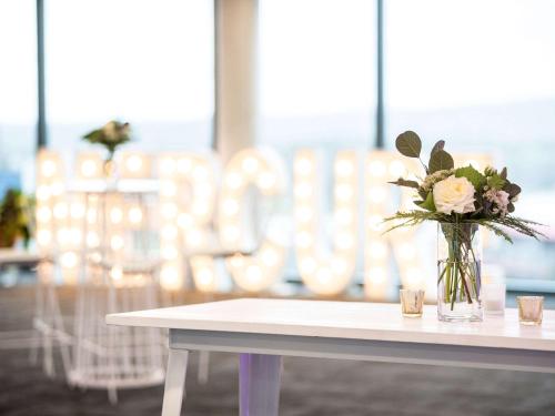 a vase filled with flowers sitting on a table at Mercure Canberra Belconnen in Canberra