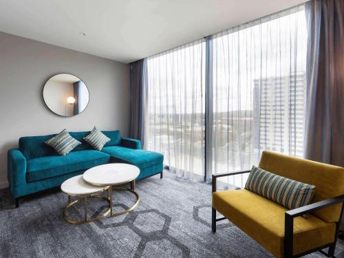 a living room with a couch and a table at Mercure Canberra Belconnen in Canberra