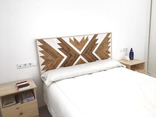 sypialnia z białym łóżkiem z drewnianym zagłówkiem w obiekcie Casita cerca de la playa decorada con amor w mieście Tarifa