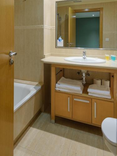 a bathroom with a sink and a tub and a mirror at Apartamentos Trisquel in Sanxenxo