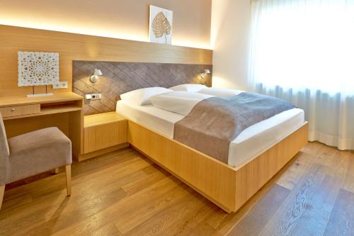 una camera con un grande letto e una sedia di Hotel Post Gries a Bolzano