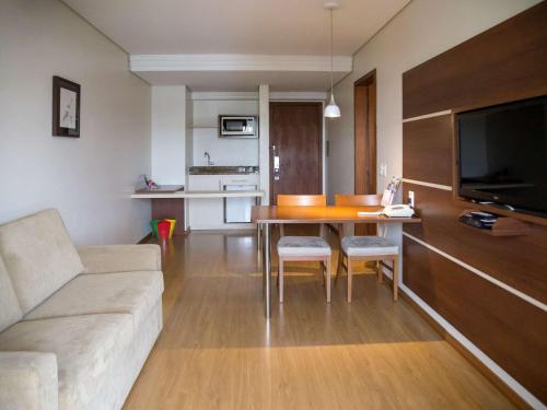 a living room with a couch and a table with chairs at Mercure Curitiba Golden in Curitiba