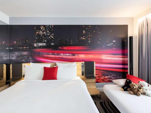 a bedroom with two beds and a painting of a city at Novotel Bordeaux Centre Ville in Bordeaux