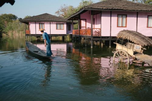 a man in a canoe in the water near a house at ViewPoint Ecolodge in Nyaung Shwe