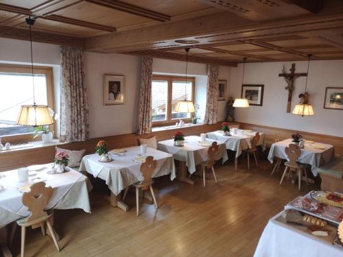a restaurant with white tables and chairs and windows at Active B&B Prairerhof in Schenna