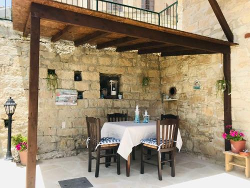 una mesa y sillas en un patio con una pared de piedra en Vouni Clock House, en Vouni