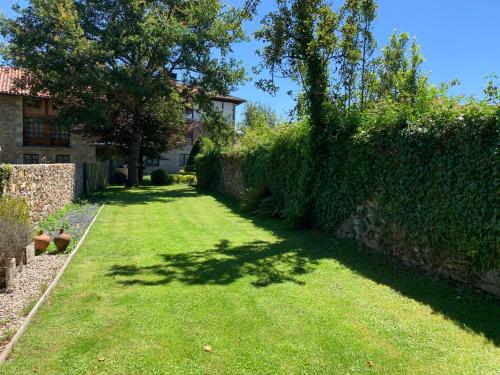 a garden with a hedge and a yard with green grass at Casa Otxandi in Ochandiano