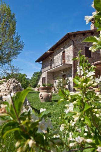 an old stone building with a yard with flowers at Relais Parco Del Subasio in Piano Delle Pieve