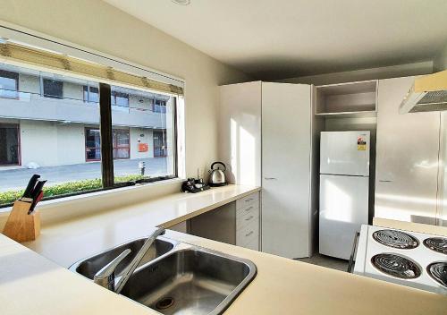 a kitchen with a sink and a white refrigerator at Airways Motel in Christchurch