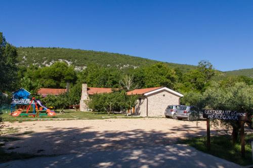 a park with a playground and a house and a sign at Rooms Hercegovka in Čapljina