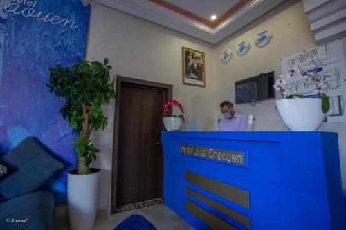kobieta stojąca za niebieskim blatem w salonie w obiekcie Hotel Jibal Chaouen w mieście Szafszawan
