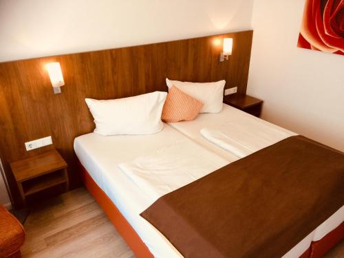 een slaapkamer met een bed met witte lakens en oranje kussens bij Triton in Keulen