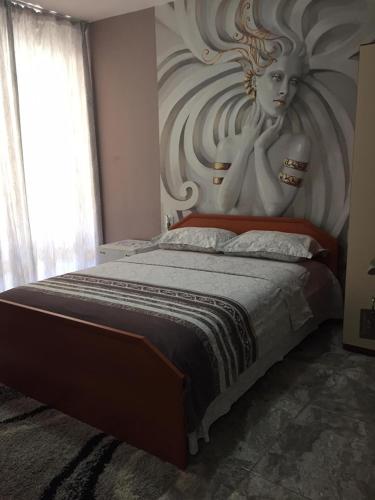 a bedroom with a bed with a painting of a woman at Къща за гости ЕЛИ in Primorsko