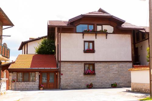 una casa de ladrillo con ventanas y cajas de flores. en Grancharova Guest House, en Bansko