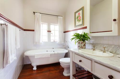 a bathroom with a tub and a toilet and a sink at Brooklyn Manor in Pretoria