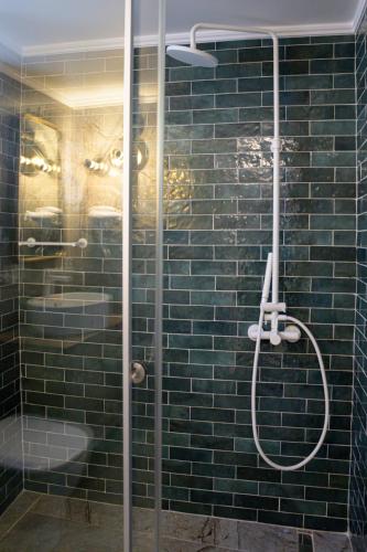 a green tiled bathroom with a shower with a glass door at The Well View in Preveza