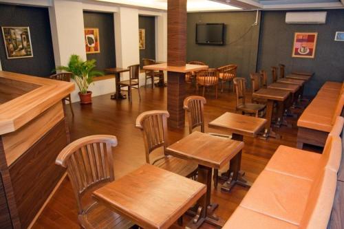 una sala da pranzo con tavoli e sedie in legno di Hotel Rumah Shinta a Giacarta