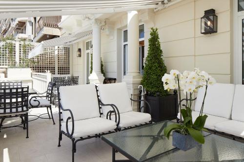 a patio with white chairs and a glass table at Hotel Boutique Villa Favorita in Donostia-San Sebastián