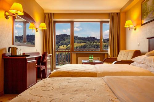 a hotel room with two beds and a large window at Hotel Gołębiewski Wisła in Wisła