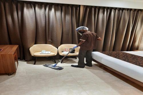 a man with a vacuum cleaner in a hotel room at Hotel Radiance in Ahmadnagar