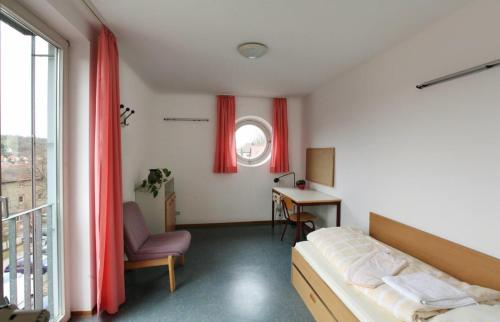 1 dormitorio con cama, escritorio y ventana en Gästehaus Goethe-Institut Schwäbisch Hall, en Schwäbisch Hall