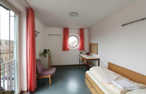 une chambre avec un lit, un bureau et une fenêtre dans l'établissement Gästehaus Goethe-Institut Schwäbisch Hall, à Schwäbisch Hall