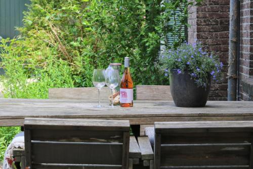 een fles wijn en twee glazen op een houten tafel bij Het Doktershuys in Gieten