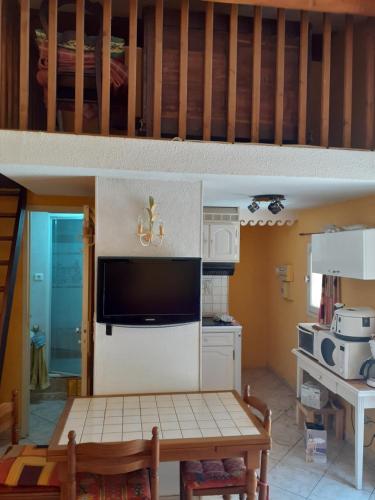 Il comprend une cuisine avec une table et une télévision murale. dans l'établissement tres beau T1, à Hyères