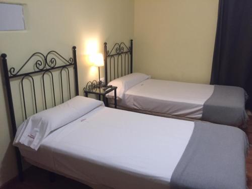 two beds in a room with white sheets at Hospederia Luis de Góngora in Córdoba