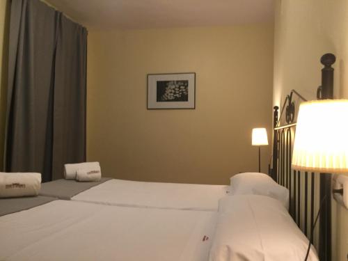 una habitación de hotel con 2 camas blancas y una lámpara en Hospedería Luis de Góngora en Córdoba