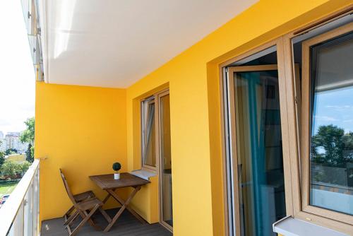 a balcony with a table and a chair on a yellow wall at Apartament SUNtorini in Kołobrzeg