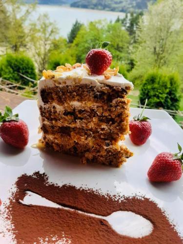 a piece of cake with strawberries on a plate at Pensiunea Lostrita in Buhalniţa